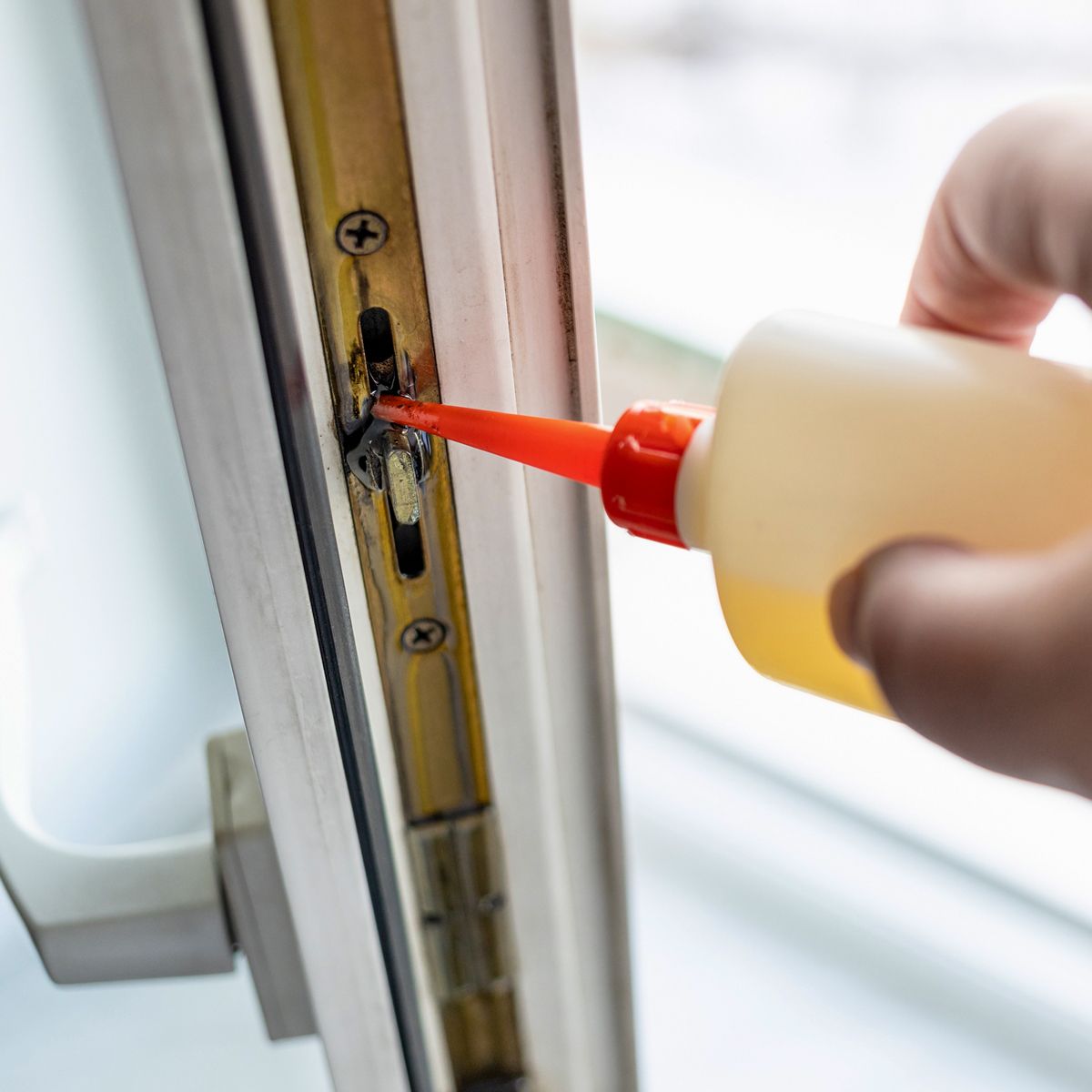 Wartung der Fenstermechanik: Beschlag am Fensterflügel wird mit Schmieröl geschmiert