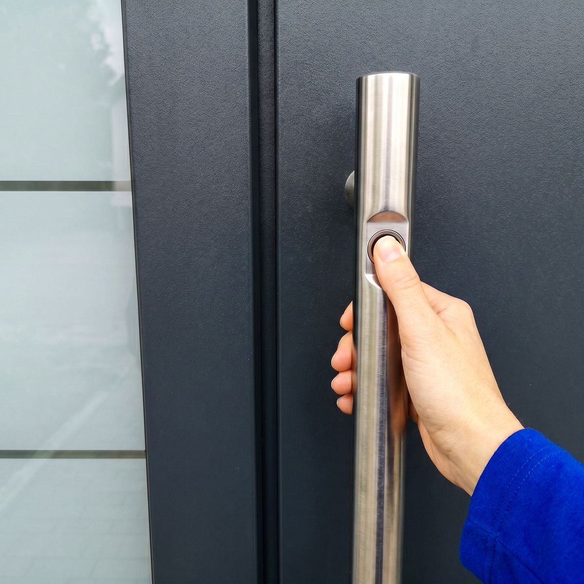 Hand legt Finger auf den Fingerabdruck-Sensor im Edelstahl-Stoßgriff einer Smart-Home-Haustür