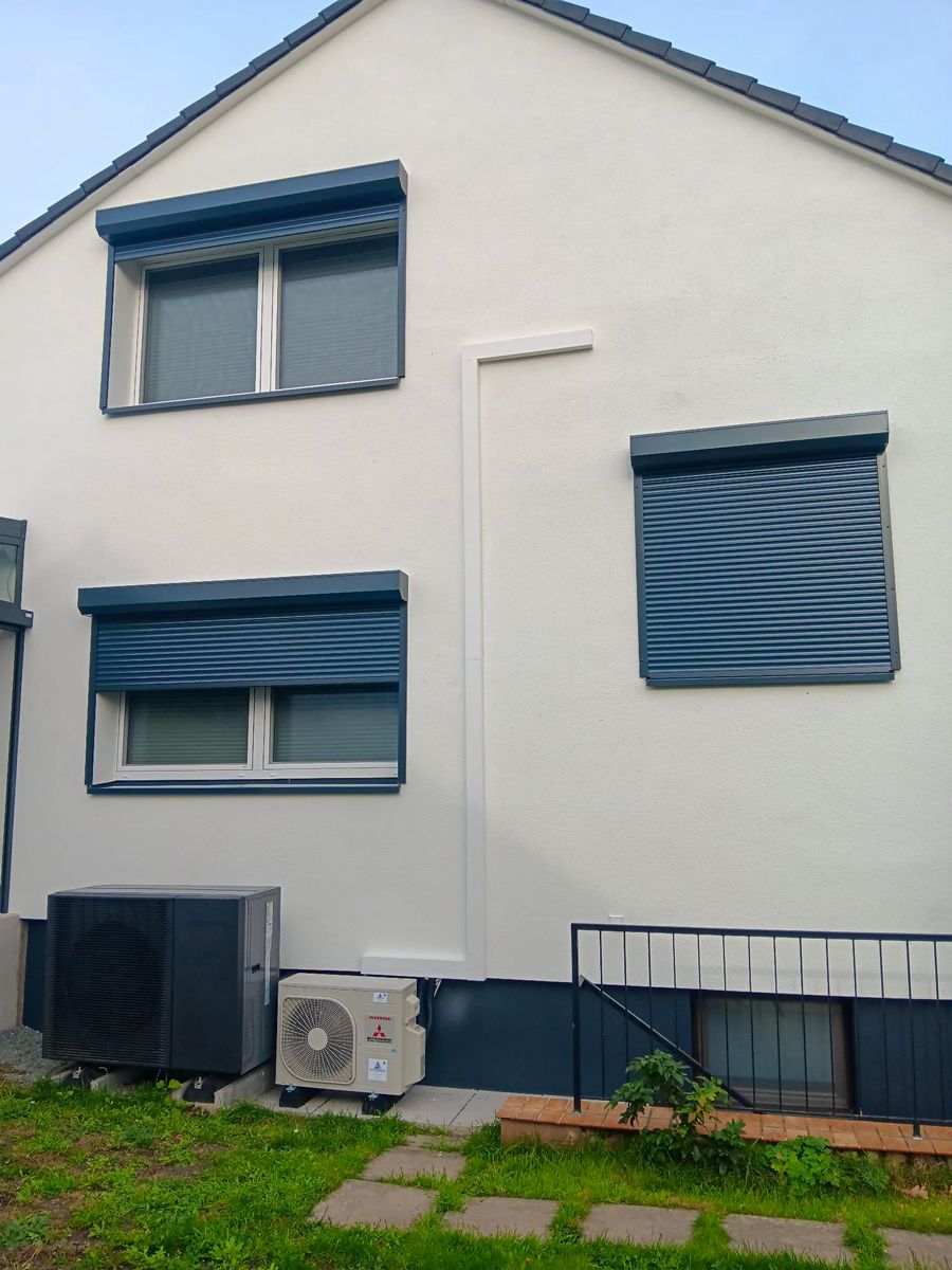 Dunkelblaues Kunststofffenster mit integriertem Rollladenkasten an heller Putzfassade