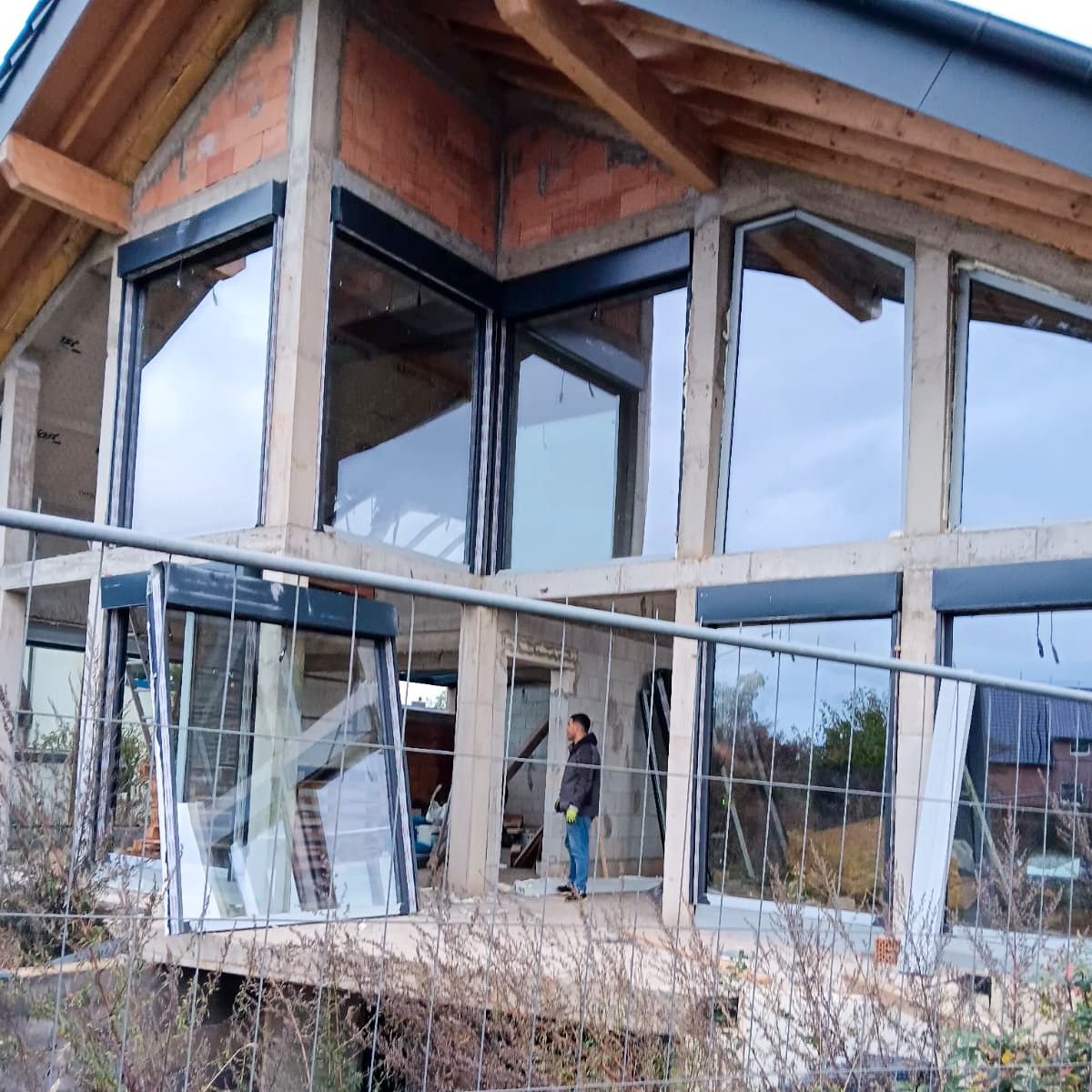 Anthrazitfarbene Glasfront mit feststehenden bodentiefen Fenstern und Terrassentüren im Rohbau