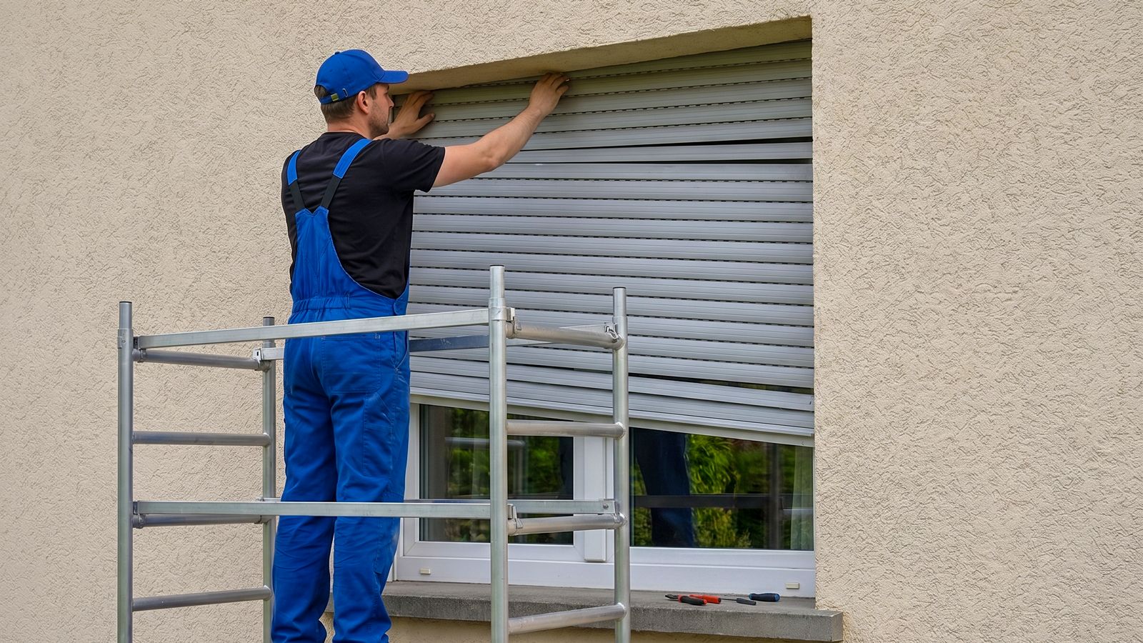 Monteur auf Arbeitsbühne repariert einen Rollladenkasten an einer Putzfassade in Pfungstadt