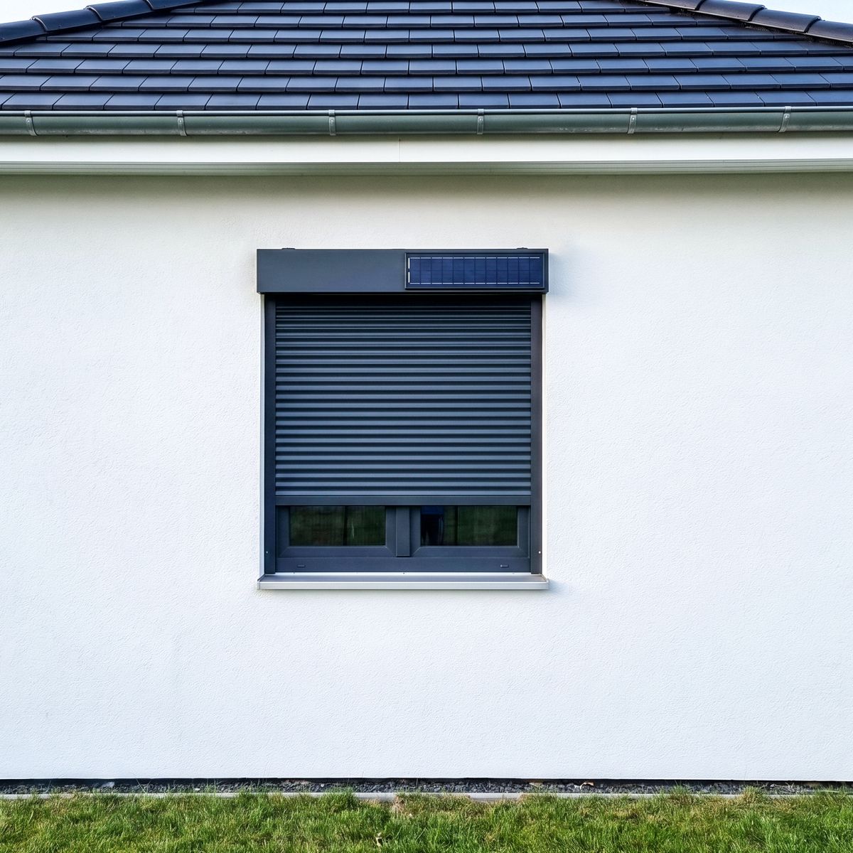 Solar-Rollladenkasten mit integriertem Solarmodul an einer weißen Putzfassade — Strom für den Antrieb ohne zusätzliche Verkabelung