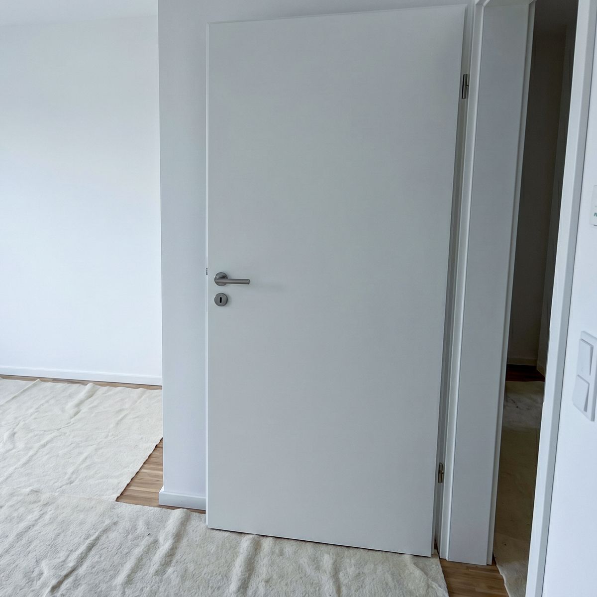 Frisch eingebaute weiße Zimmertür im Neubau, Boden mit Abdeckvlies geschützt