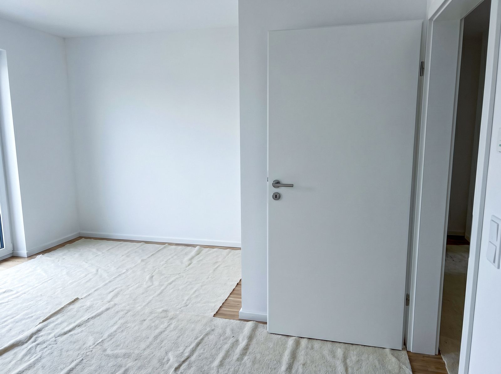 Frisch eingebaute weiße Zimmertür im Neubau, Boden mit Abdeckvlies geschützt