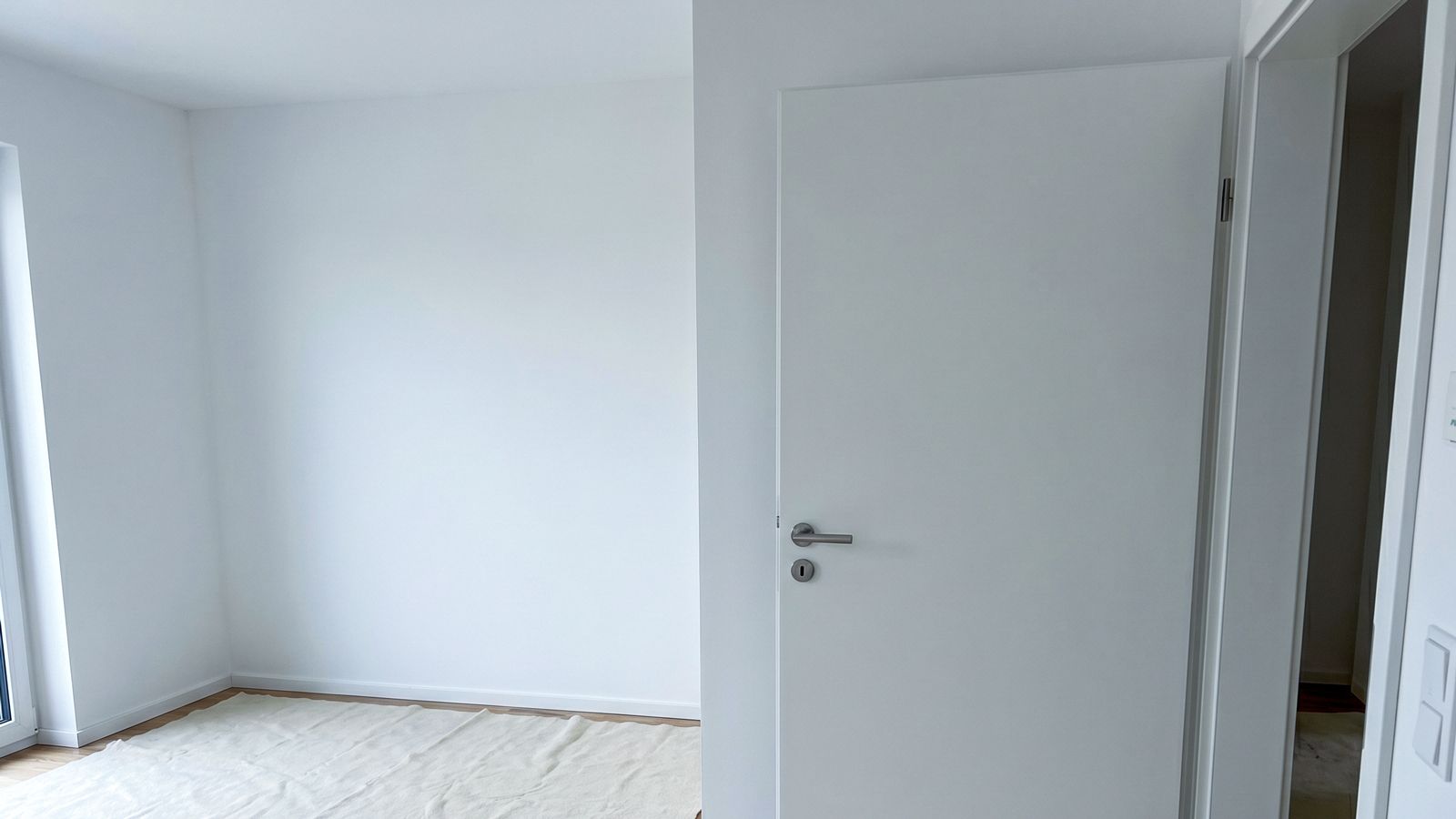 Frisch eingebaute weiße Zimmertür im Neubau, Boden mit Abdeckvlies geschützt